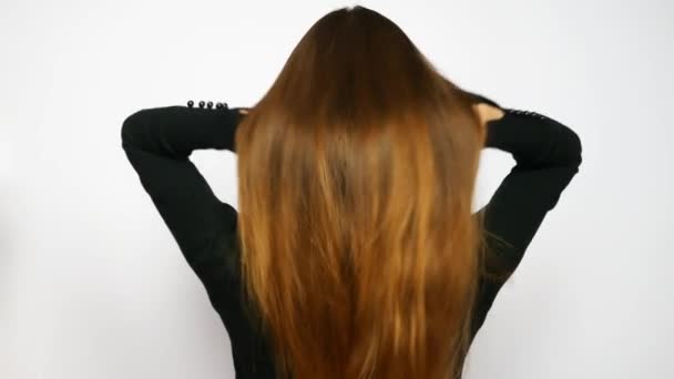 Egy fiatal, gyönyörű nő kiegyenesíti hosszú, fényűző haját.
