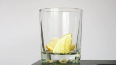 Birisi limonlu bardağa viski ya da konyak dolduruyor.