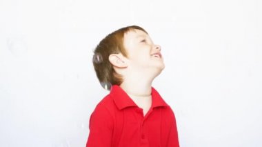 Güzel küçük bir çocuk sabun köpüklerinin ve sevinçlerin yağmurunda duruyor.