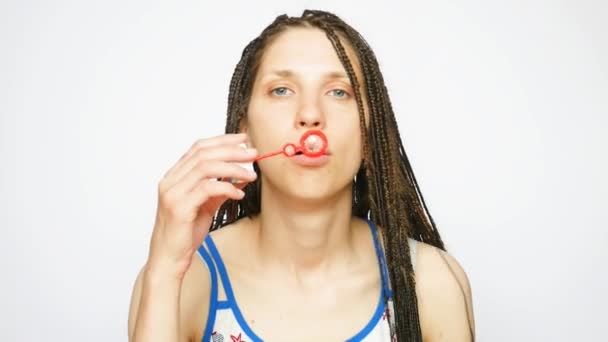 Eine Schöne Dame Mit Zöpfen Pustet Seifenblasen Vor Weißem Hintergrund — Stockvideo
