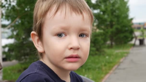 Portrait d'un beau petit garçon assis sur le banc à l'extérieur