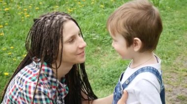 Genç ve güzel bir kadın papatya tarlasında çocuğuna sarılıyor.