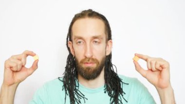 Genç ve güzel bir örgü adam bir seçim yapar ve beyaz arka planda iki meyve şekeri yer.