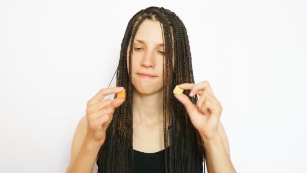 一位年轻漂亮的辫子女士做了一个选择 在白色背景下吃了两个果糖 — 图库视频影像
