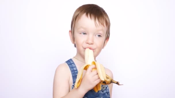 Ένα Χαρούμενο Αγοράκι Φόρμα Τρώει Μια Μπανάνα — Αρχείο Βίντεο