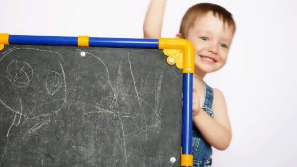 Een Schattig Jongetje Gluurt Uit Van Tekentafel Zwaait Met Een — Stockvideo