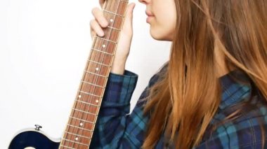 Saçları rüzgarda dalgalanan güzel bir kız gitarı nazikçe okşar.