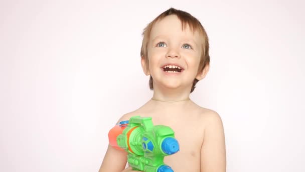 一个拿着水枪的快乐的小男孩微笑着抬起头 — 图库视频影像