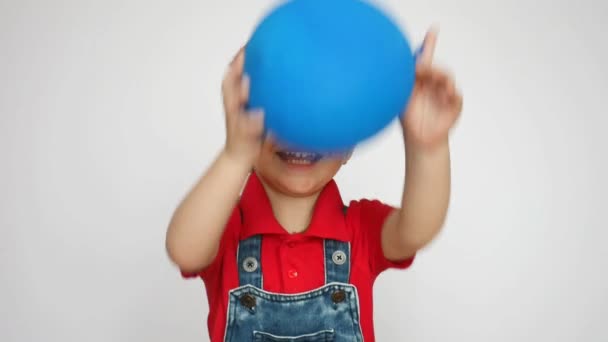Счастливый Маленький Мальчик Поднимает Синий Шарик Бросает — стоковое видео