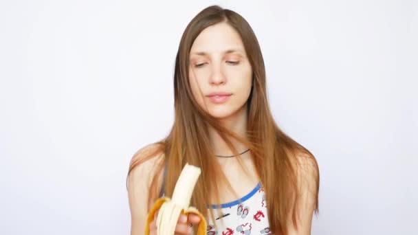一位年轻貌美的女士在白色背景下吃香蕉 — 图库视频影像