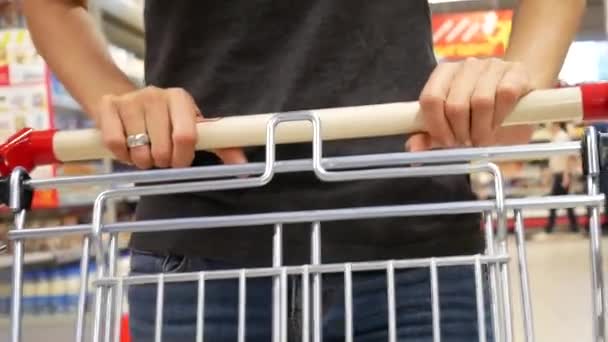 一个漂亮的女孩在超级市场转着购物车 — 图库视频影像
