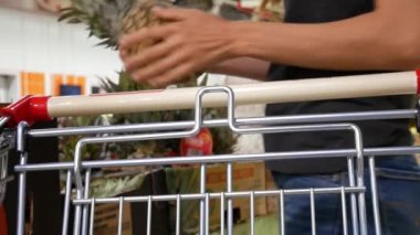 Güzel bir kız markette plastik bir torbaya olgun bir ananas koyar.