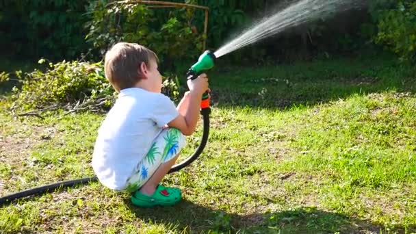 Liten Pojke Vatten Trädgård Växter Med Vattning Spray Sitter Gräset — Stockvideo