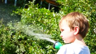 Küçük bir çocuk bahçe bitkilerini sulandırıyor.
