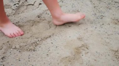 Küçük bir çocuğun kumsalda iki adım atması