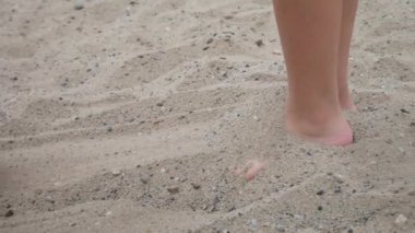 Bir kadının eli, çocuğun ayaklarını kuma gömer ve o da içinden fırlar.