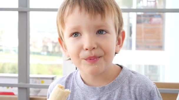 Ett Porträtt Söt Pojke Som Äter Banan Och Ler Nära — Stockvideo