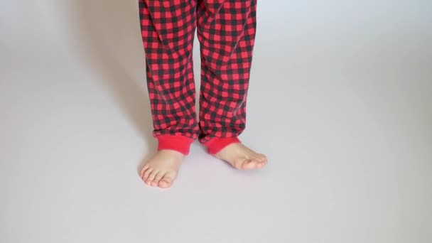 Menino Vestindo Calças Xadrez Vermelho Pisca Superfície Branca — Vídeo de Stock