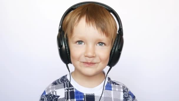 Beyaz Arka Planda Büyük Kulaklıkları Olan Mutlu Küçük Bir Çocuğun — Stok video