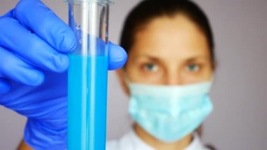 Güzel bir laboratuvar asistanı bir test tüpünü mavi bir sıvıyla tutar ve sonra doldurur.