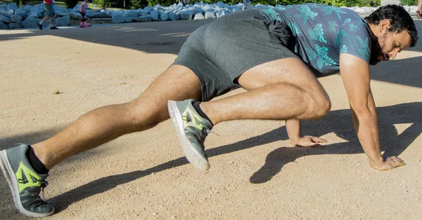 Man playing sports in a park in the afternoon and wearing a flower T-shirt