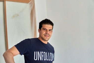 Bir odayı boyarken mavi gömlekli bir işçinin portresi