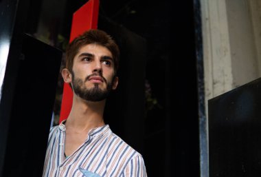 Siyah ve kırmızı arka planı ve büyüleyici görünüşü olan bir çocuk.