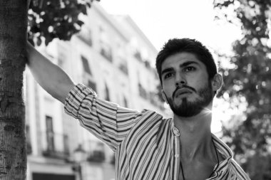 Madrid sokaklarında baştan çıkarıcı bakışlarla poz veren genç bir çocuk.