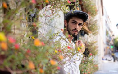 Etrafı renkli çiçeklerle çevrili, Madrid 'de beyaz mumya olan genç bir çocuk.