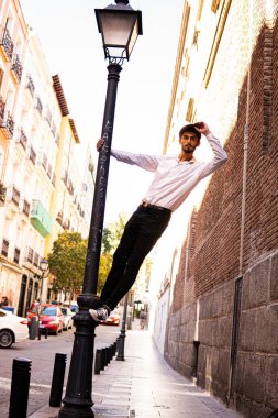 Madrid sokaklarında sokak lambası kullanan bereli genç bir çocuk.
