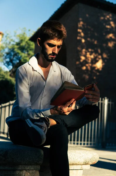 Madrid 'de bir parkta kırmızı kitap okuyan genç bir çocuk.