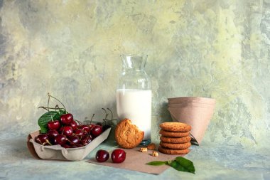 Lezzetli kurabiyeler, sütle dolu cam bir şişe, kiraz meyveleri, soyut ve güzel bir arka planda metnin için fotokopi alanı. seçici odak.