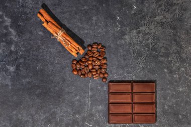Kahve çekirdekleri, tarçın çubukları ve koyu grafit arkaplanda çikolata. seçici odak.