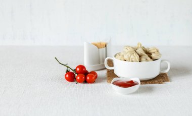 Hafif arkaplanda kompozisyon, içinde et ve kiraz domatesli ravioli köftesi olan bir fincan. Evde lezzetli yemekler pişirme kavramı. Seçici odak.