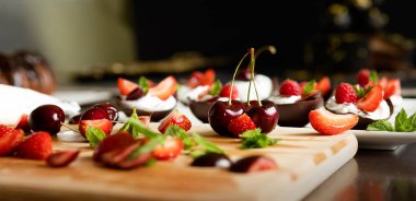 Tatlı olarak el yapımı çikolata bardaklarını çırpılmış krema ve böğürtlenlerle hazırlama ve dekore etme süreci. Lezzetli bir yaz tatili konsepti. seçici odak. 