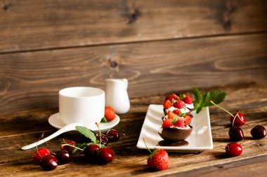 Ahşap zemin üzerinde krem şanti ve böğürtlen bulunan el yapımı çikolata bardakları. Lezzetli bir yaz çay partisi konsepti. seçici odak. 