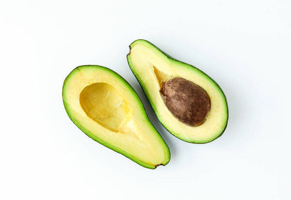 two halves of fresh green avocado isolated on a white background.
