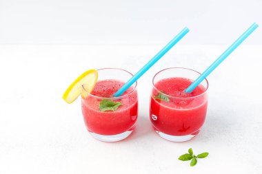 Açık arkaplanda limon dilimleri olan cam bardakta karpuz püresi. Işık, yaz, sağlıklı yiyecek kavramı..