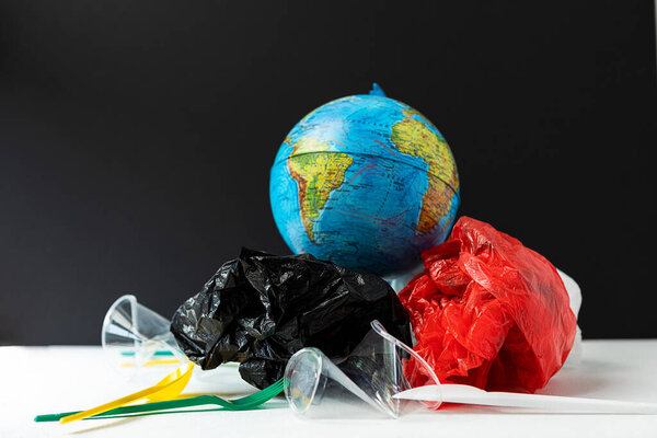 Глобус окружен пластиковым мусором. Концепция глобального загрязнения окружающей среды и спасения планеты.