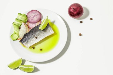 Baharatlı tuzlu ringa balığı, limon dilimleri ve beyaz arka planda kırmızı soğan halkaları. kopyalama alanı. Düz yatıyordu.