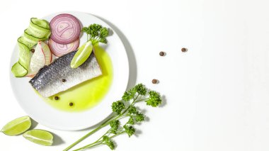 Baharatlı tuzlu ringa balığı, limon dilimleri ve beyaz arka planda kırmızı soğan halkaları. kopyalama alanı. Düz yatıyordu.