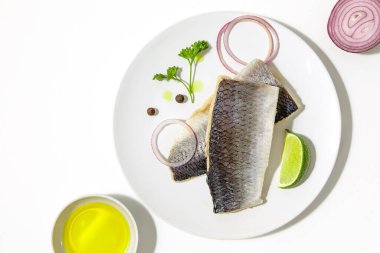 Baharatlı tuzlu ringa balığı, limon dilimleri ve beyaz arka planda kırmızı soğan halkaları. kopyalama alanı. Düz yatıyordu.