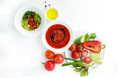 Olgun, parlak sebzeler, malzemeler ve beyaz bir fonda soğuk gazpacho çorbası. Vejetaryen ve vejetaryen yemekleri.