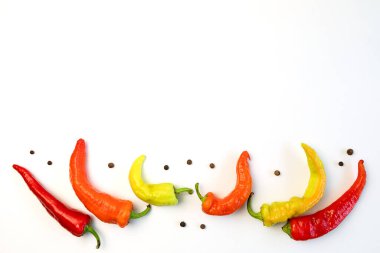 Sarı, turuncu ve kırmızı biberler beyaz bir masada. Hasat mevsimi kavramı, aydınlık sonbahar.