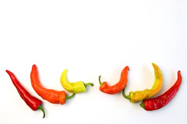 Sarı, turuncu ve kırmızı biberler beyaz bir masada. Hasat mevsimi kavramı, aydınlık sonbahar.