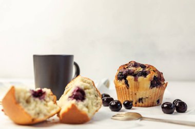 Lezzetli yaban mersinli kekler ve yaban mersinli beyaz masa, koyu kahve fincanları. seçici odak