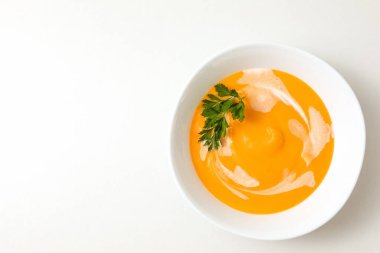 Bir kase balkabağı ya da havuçlu vejetaryen kremalı çorba taze maydanoz ve kremayla beyaz dokulu bir masada süslenir. düz alan, kopyala boşluk