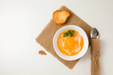 Bir kase balkabağı ya da havuçlu vejetaryen kremalı çorba taze maydanoz ve kremayla beyaz dokulu bir masada süslenir. düz alan, kopyala boşluk
