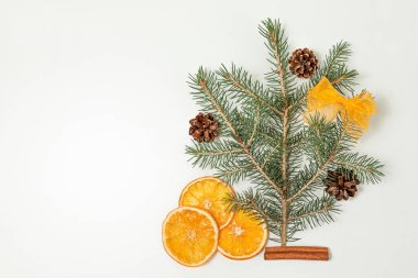 Yaratıcı, Noel ve yeni yıl kompozisyonu. Kurumuş portakal dilimleri ve beyaz arka planda çam kozalakları olan bir çam dalı. Boşluğu kopyala.