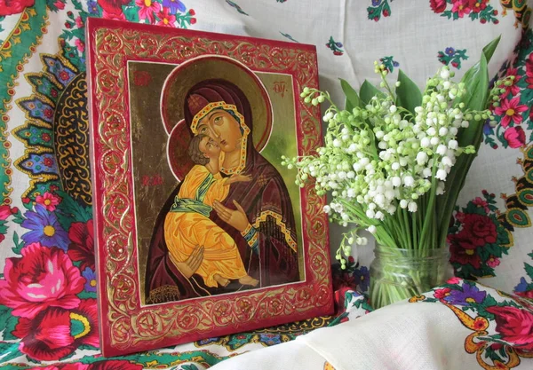 The traditional Orthodox icon of the Mother of God is Vladimirskaya. Handwritten icon of the Virgin Mary with Jesus Christ on the background of Ukrainian rushnyks and lilies of the valley. orthodox.
